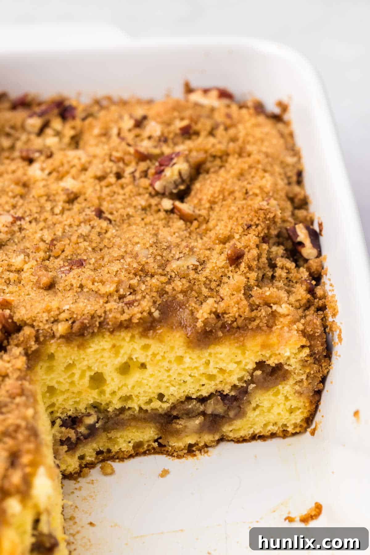 The baked coffee cake in a pan with several slices already cut out.