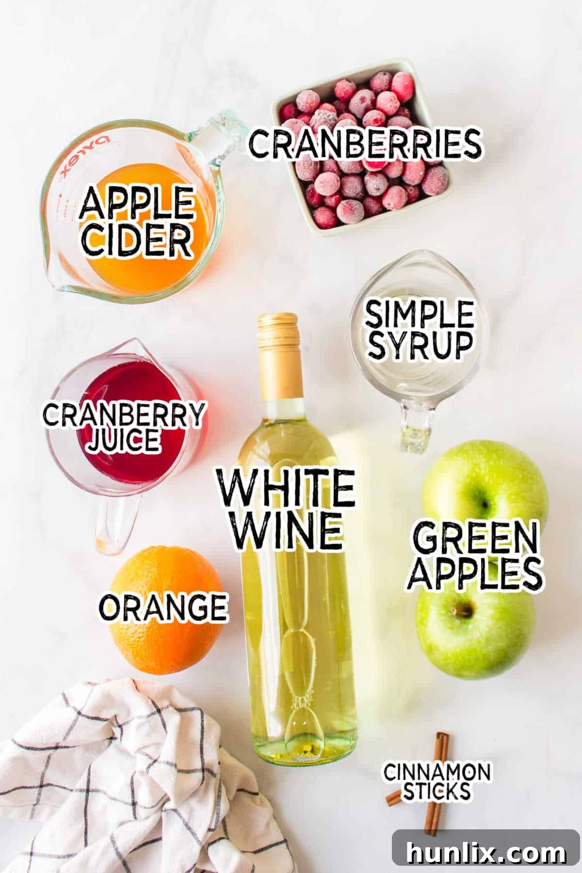 A flat lay image displaying all the ingredients for Holiday Sangria on a white background.