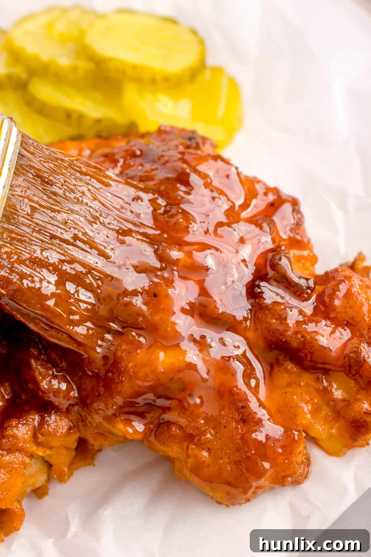 Crispy Air-Fried Nashville Heat 10 A basting brush applying the hot sauce onto a piece of Air Fryer Nashville Hot Chicken.