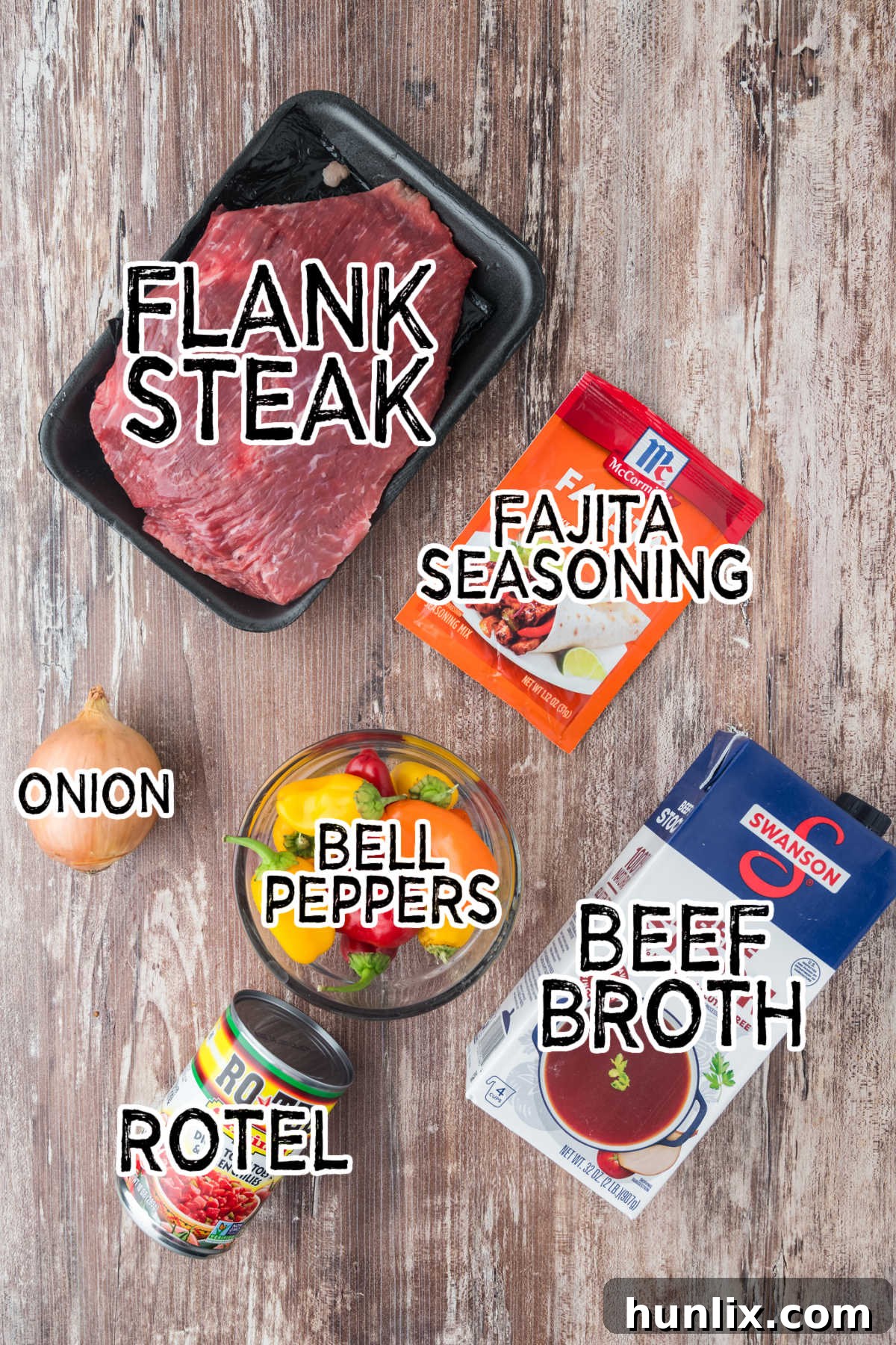 Fresh ingredients laid out for slow cooker steak fajitas preparation, including flank steak, bell peppers, onion, and spices.