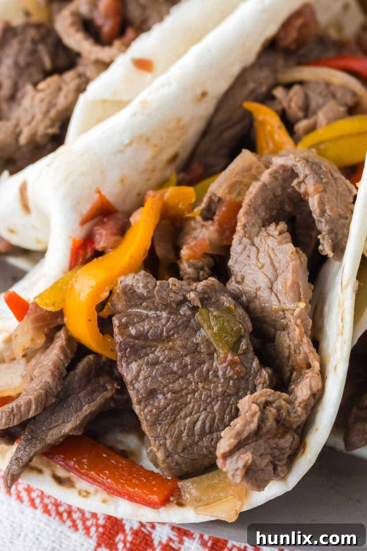 A close-up of a perfectly wrapped steak fajita in a soft tortilla, ready to eat.