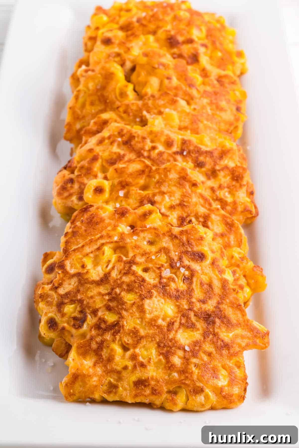 Golden Corn Bites 7 An inviting platter showcasing a generous stack of golden corn fritters, ready to be served as a delightful Southern side dish or appetizer.