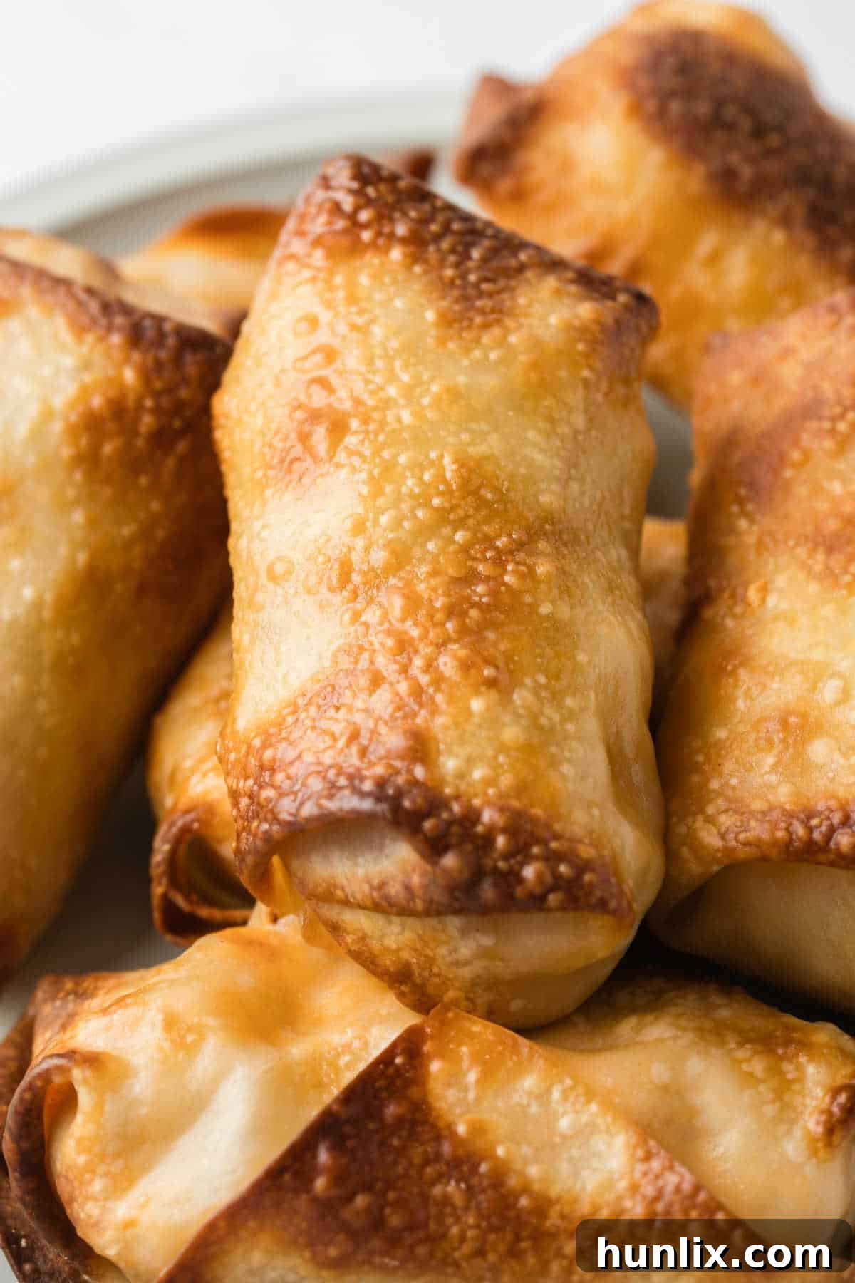 A group of golden brown, crispy Air Fryer Buffalo Chicken Egg Rolls arranged attractively on a platter.