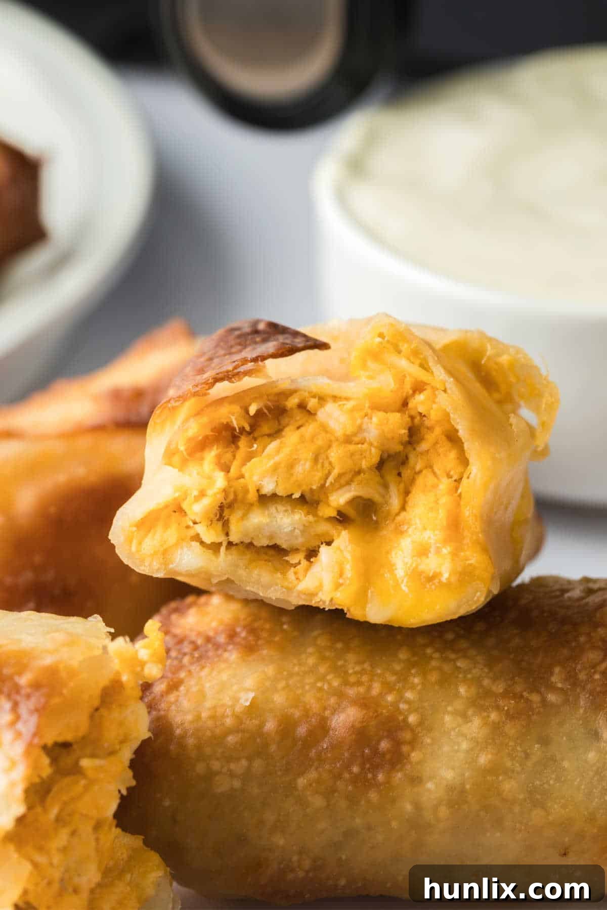 A buffalo chicken egg roll cut in half, revealing the creamy, cheesy, and spicy filling inside.