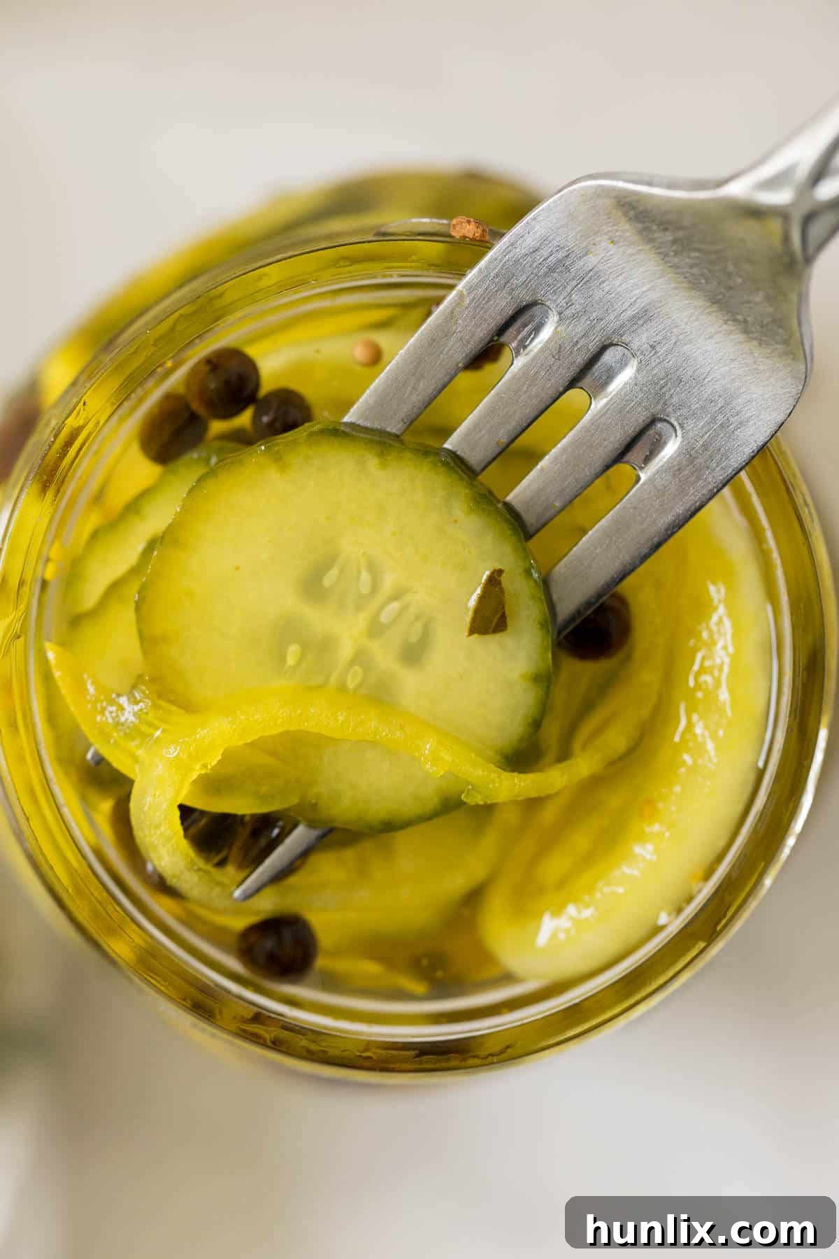 Quick and Easy Refrigerator Bread and Butter Pickles 8 A single bread and butter pickle slice on a fork, emerging from a mason jar.