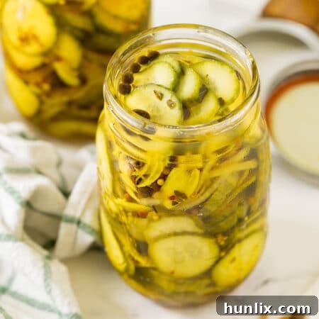 Quick and Easy Refrigerator Bread and Butter Pickles 9 A jar of refrigerator bread and butter pickles with a slice on a fork, ready to be eaten.