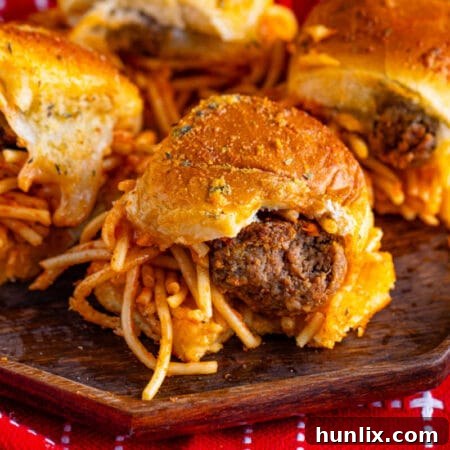 Spaghetti and meatball sliders on a wooden platter.