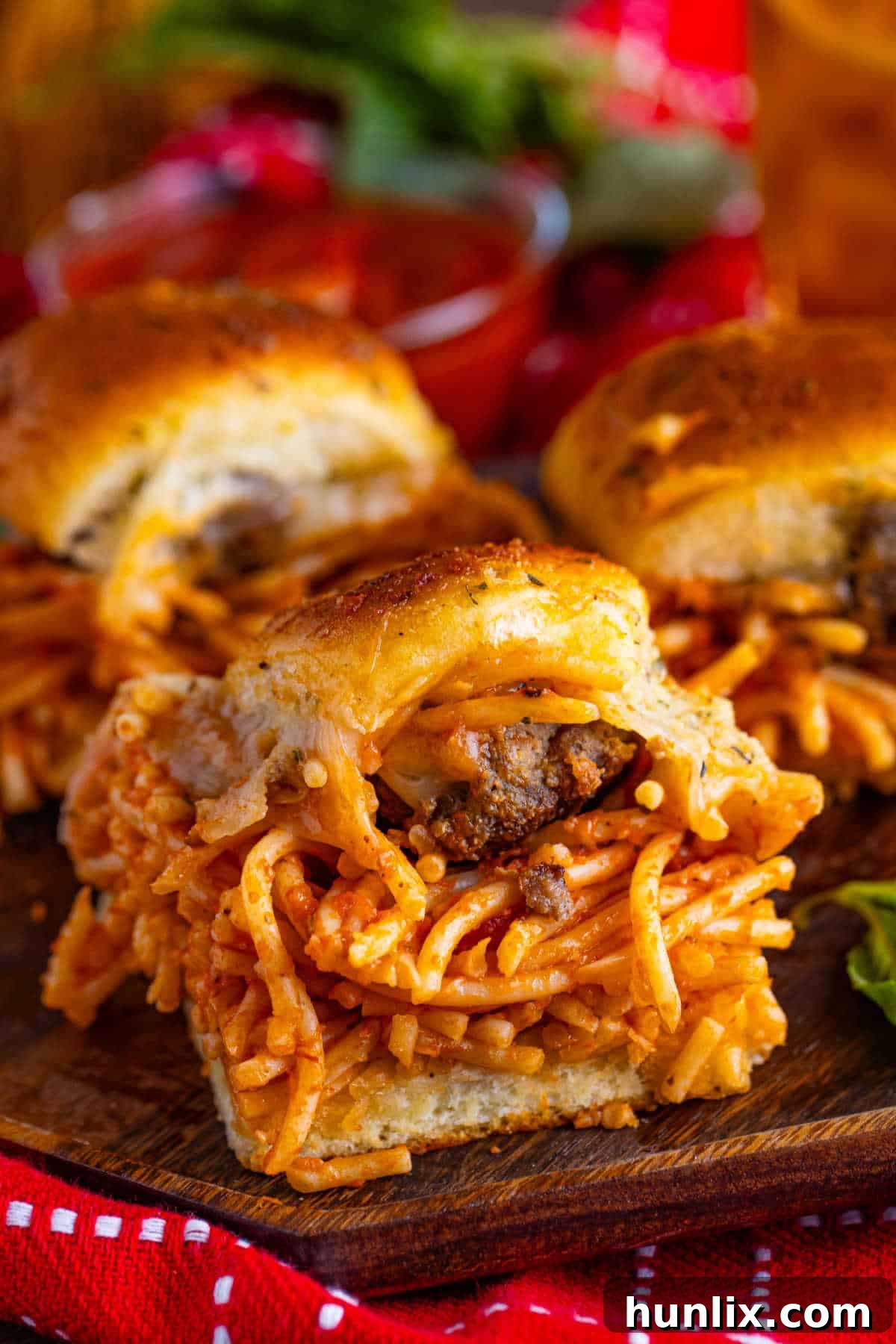 An overhead shot of spaghetti and meatball sliders on a wooden platter, ready to be enjoyed.