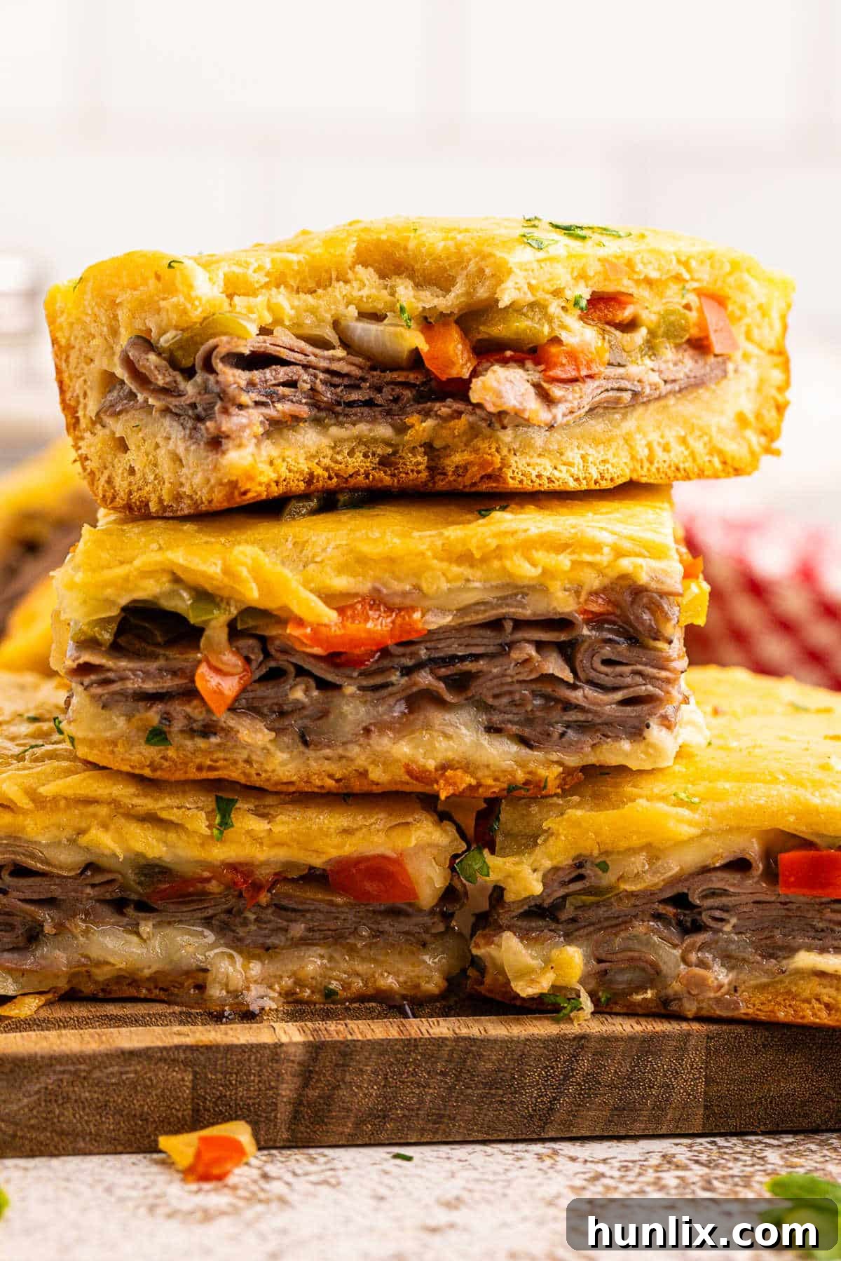 A stack of golden-brown Philly cheesesteak squares with melted cheese, arranged neatly.