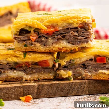 A stack of golden-brown Philly cheesesteak squares with melted cheese, arranged neatly.