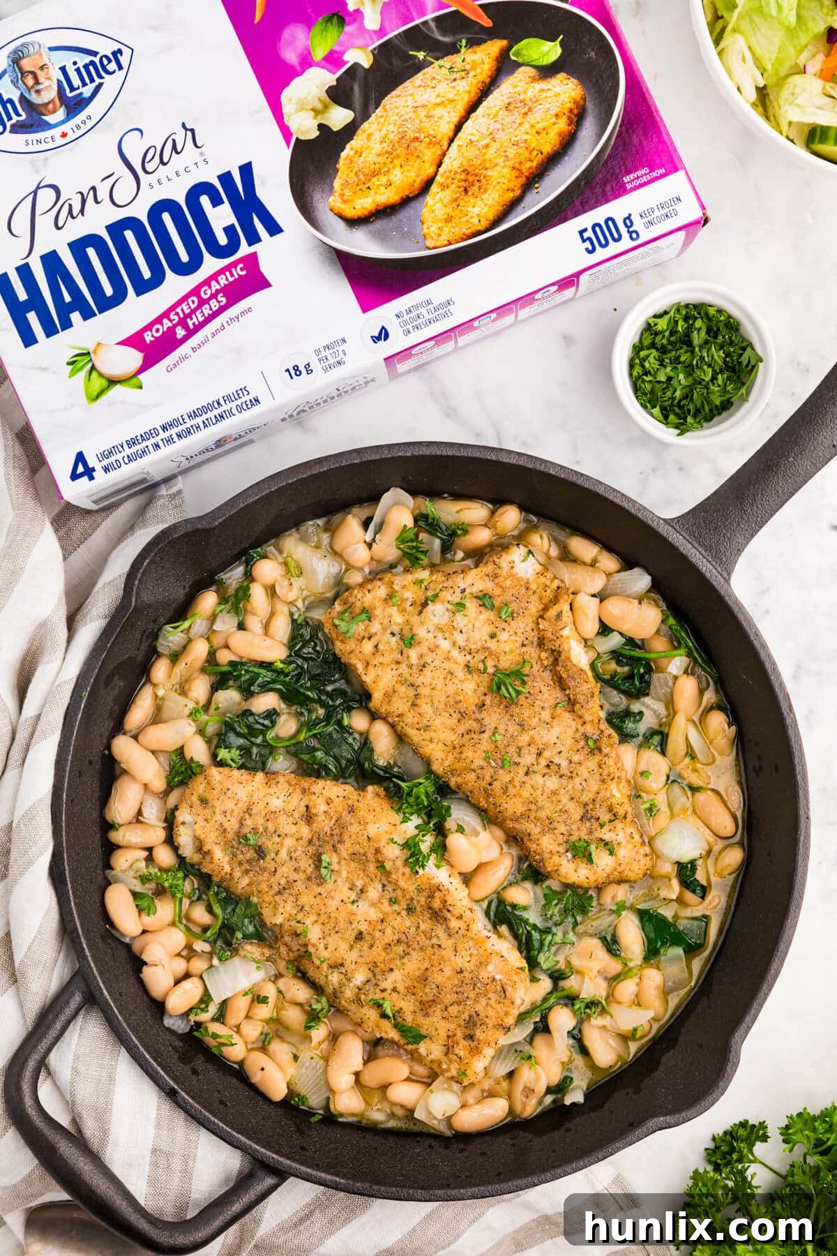 High Liner Haddock with spinach and white bean ragout in a cast iron pan, ready to serve.