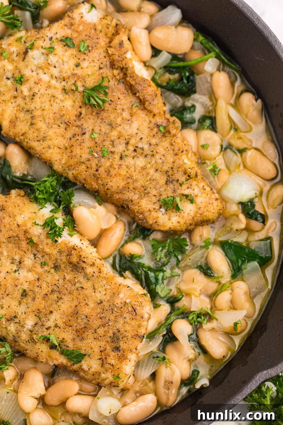 Serving of High Liner Haddock with spinach and white bean ragout in a cast iron pan.