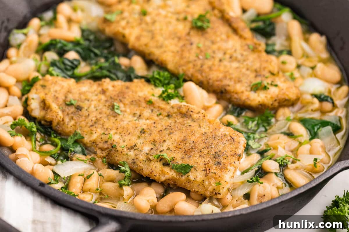 Close-up of High Liner Haddock with spinach and white bean ragout in a cast iron pan, showing texture.