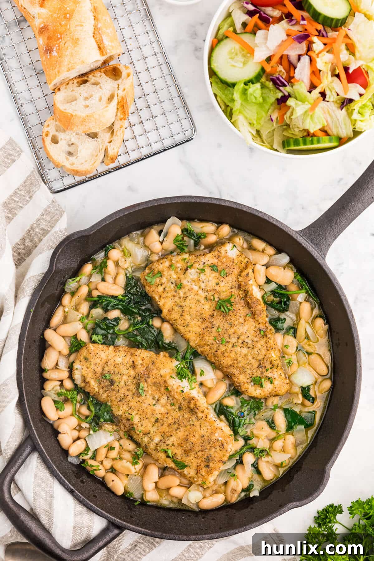 High Liner Haddock with spinach and white bean ragout in a cast iron skillet, close-up.
