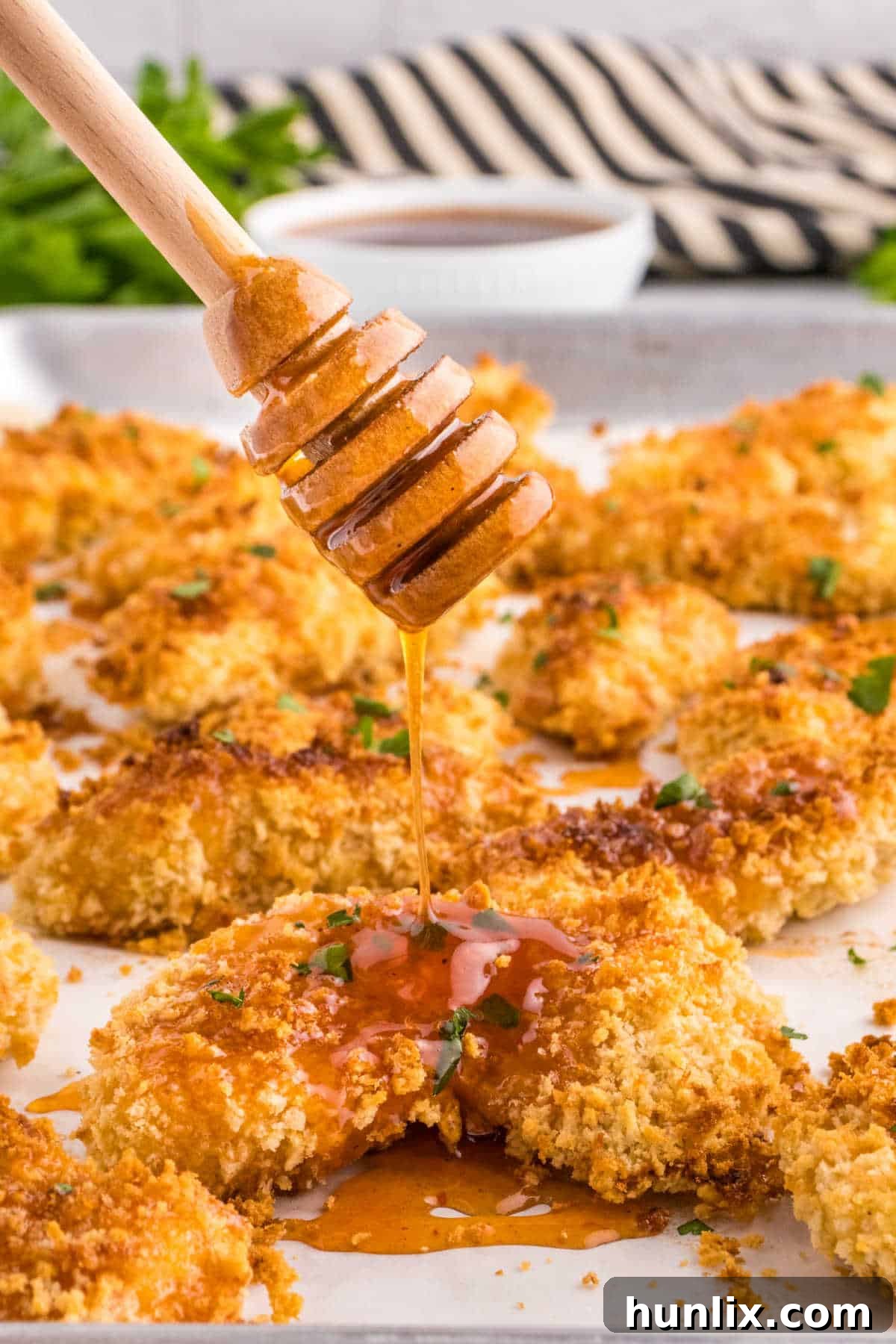 Hot honey sauce being drizzled on chicken tenders.
