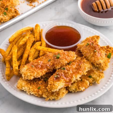 Hot honey chicken tenders on a plate with fries and hot honey sauce.