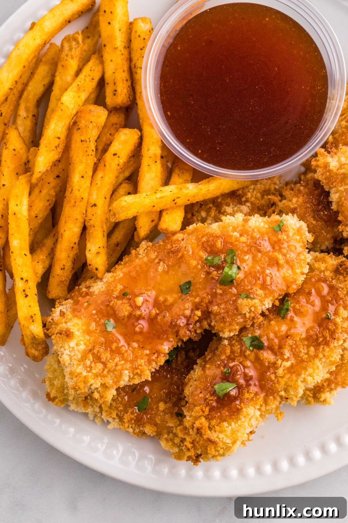 Hot honey chicken tenders on a plate with fries and hot honey sauce.