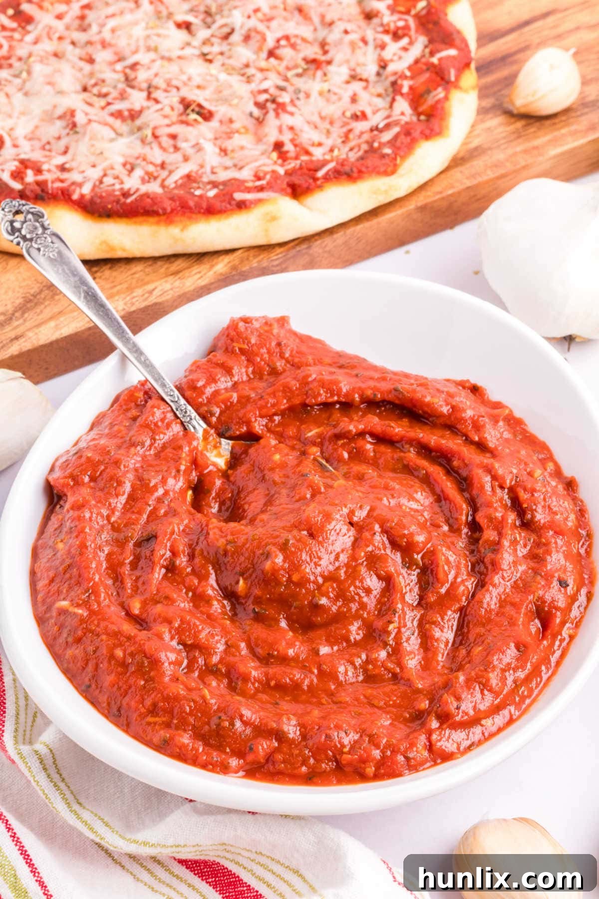 Pizza sauce in a bowl with a spoon, highlighting its thick, rich texture.