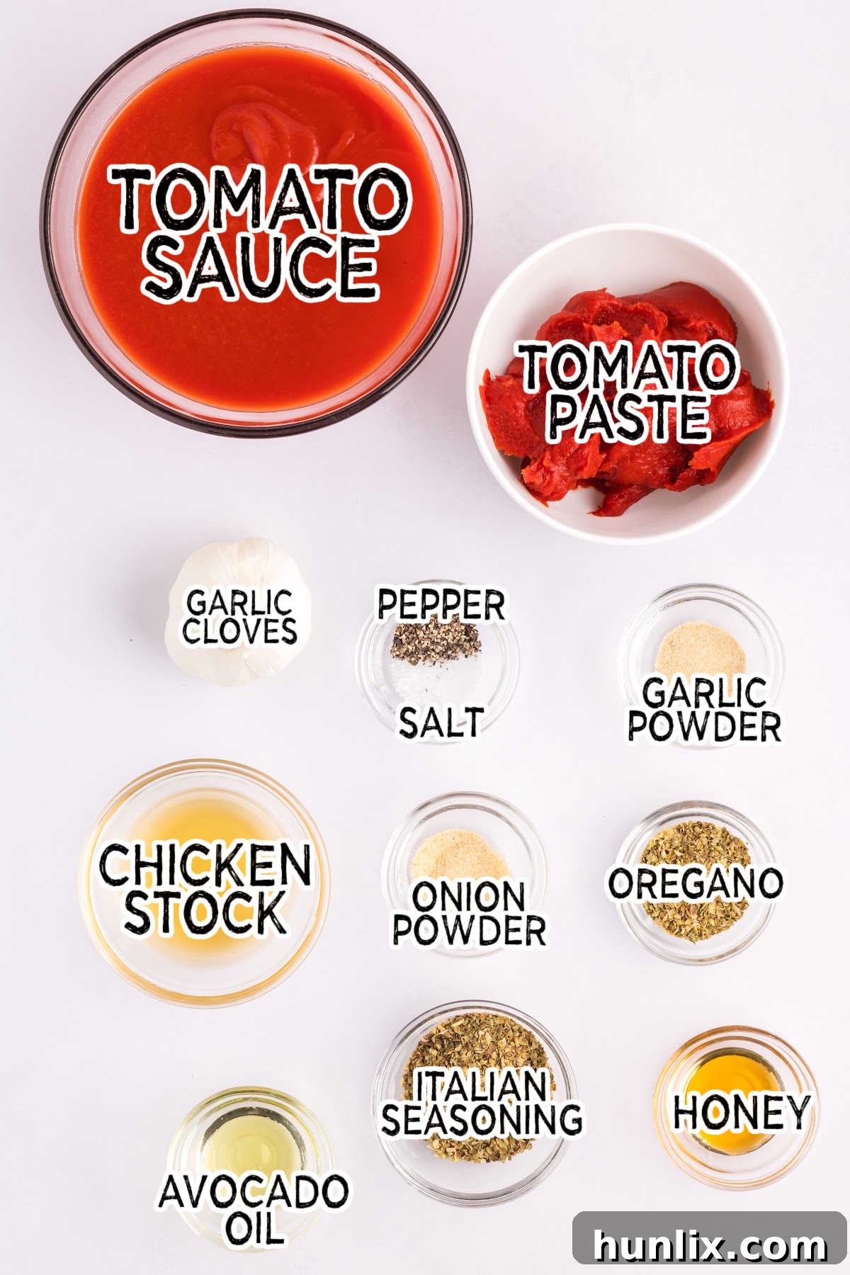 Various ingredients for pizza sauce laid out on a white surface.