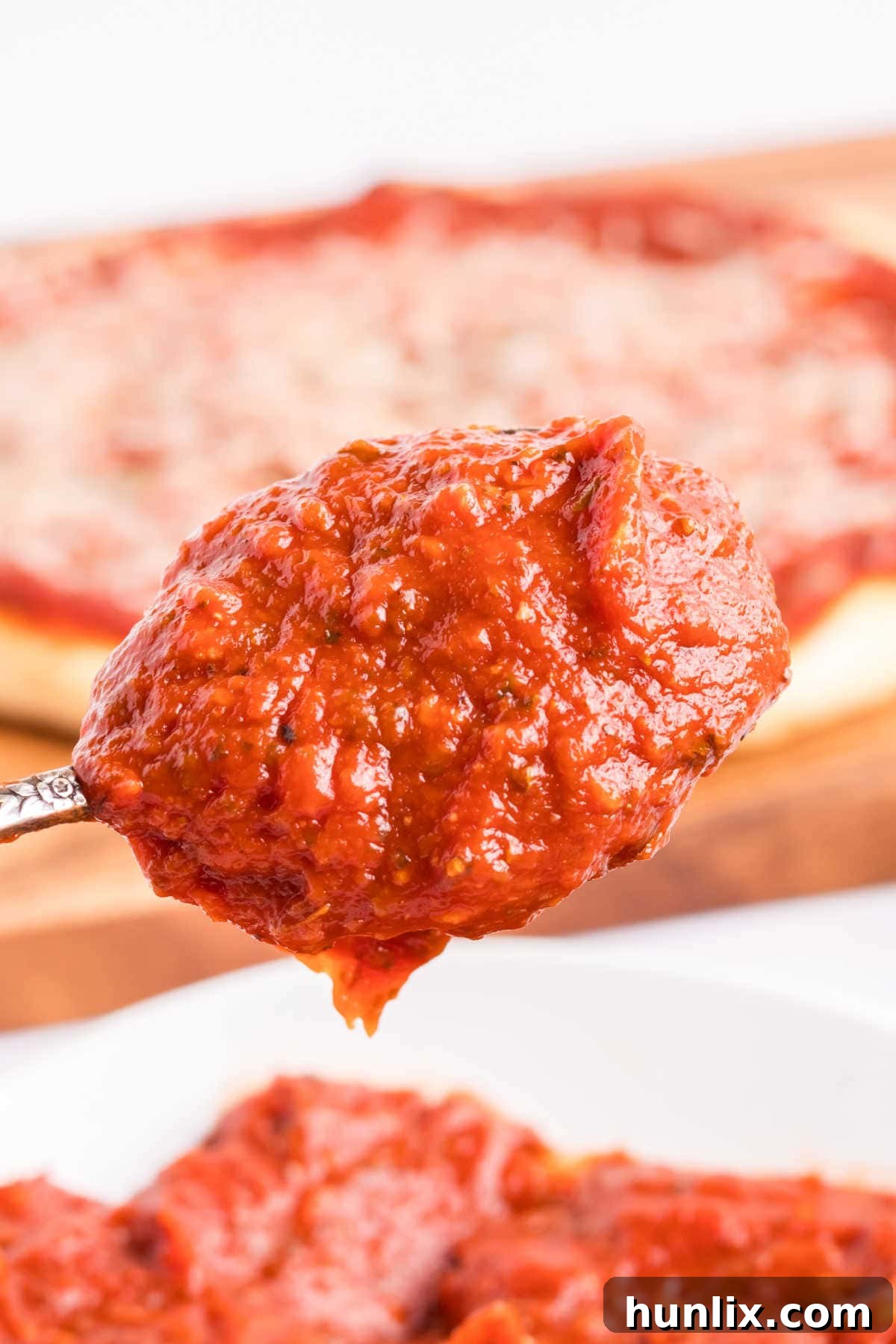 A spoon full of homemade pizza sauce, showcasing its thickness and texture.