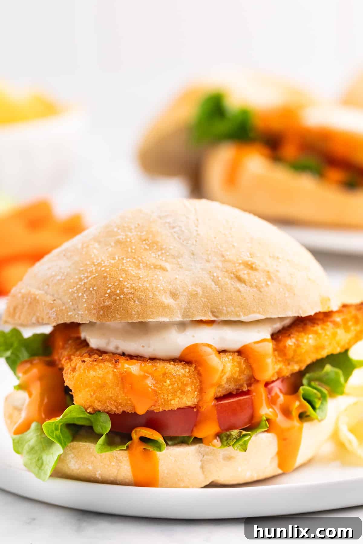 A finished buffalo cod filet sandwich on a plate.