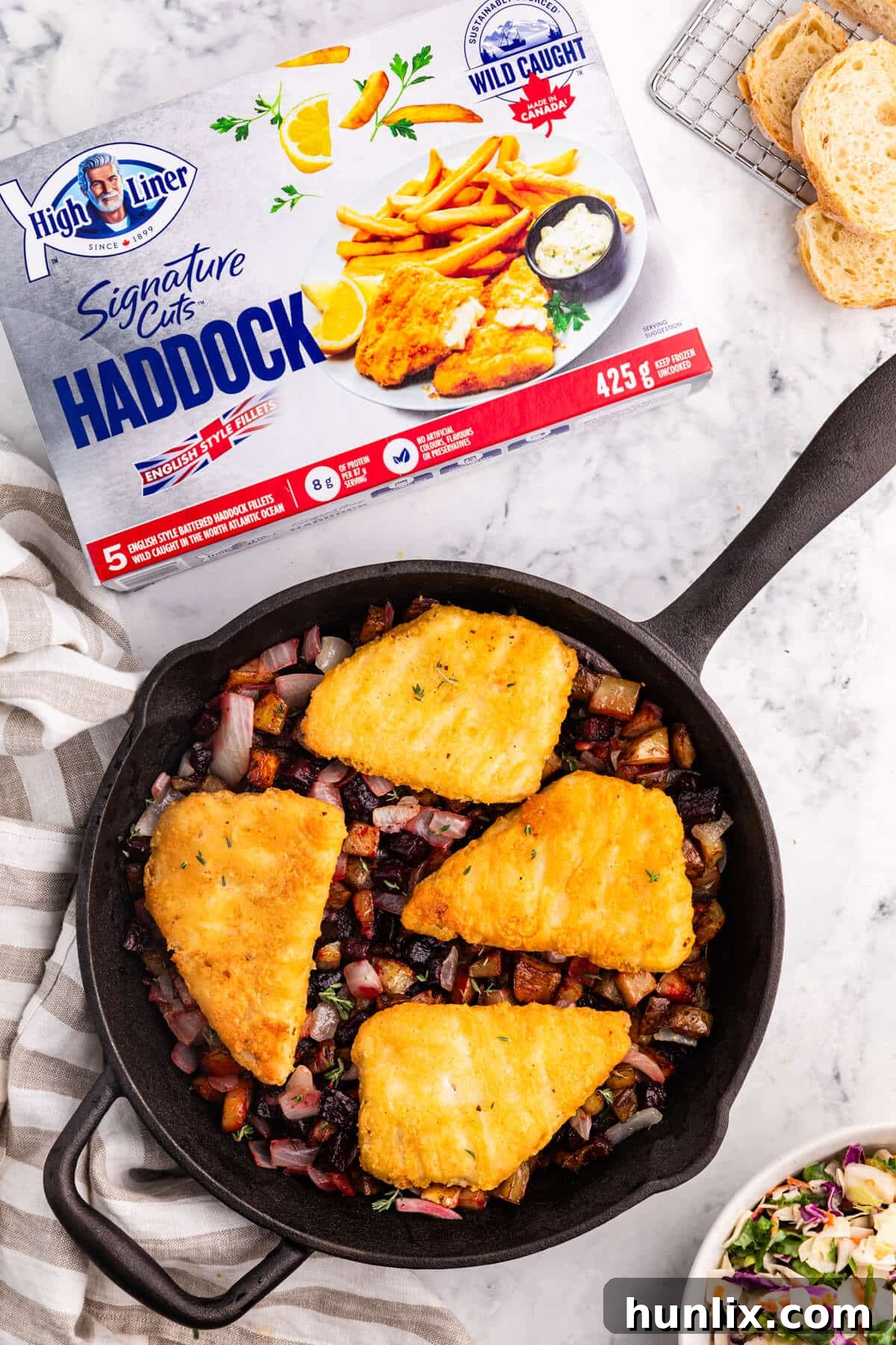 Pan-Seared Fish with Ruby Root Hash 2 Fish with beet and potato has in a pan, showcasing the vibrant colors of the hash beneath the crispy haddock fillets.