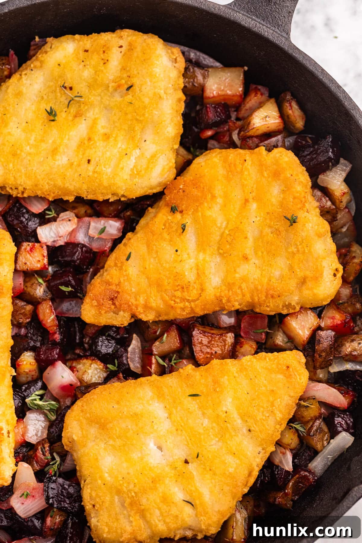 Pan-Seared Fish with Ruby Root Hash 4 Fish with Beet and Potato Hash cooking in a large pan on the stovetop, showing the combined ingredients.