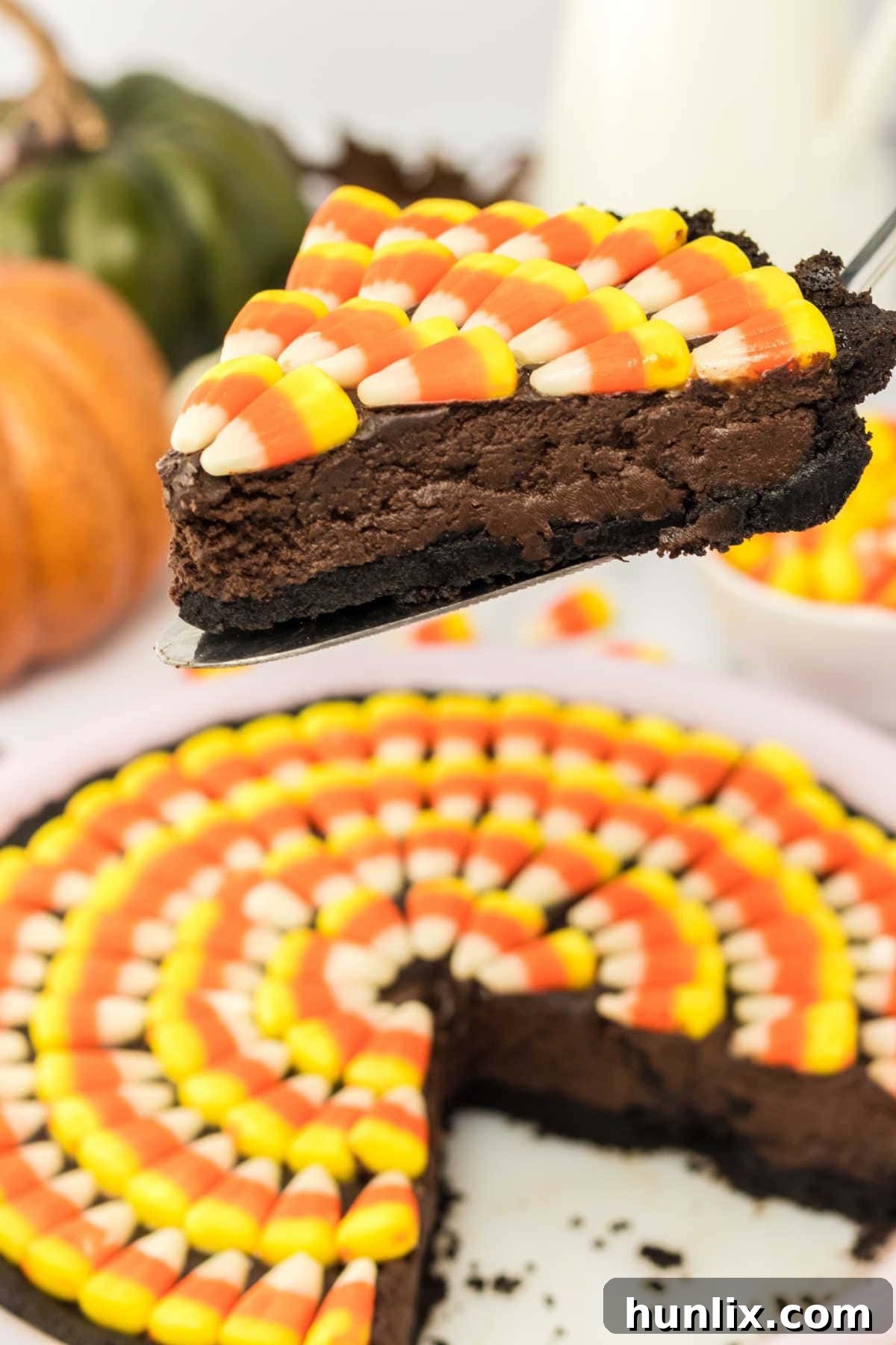 A perfectly sliced Candy Corn Pie on a pie server, showcasing its rich chocolate base and colorful candy corn topping.