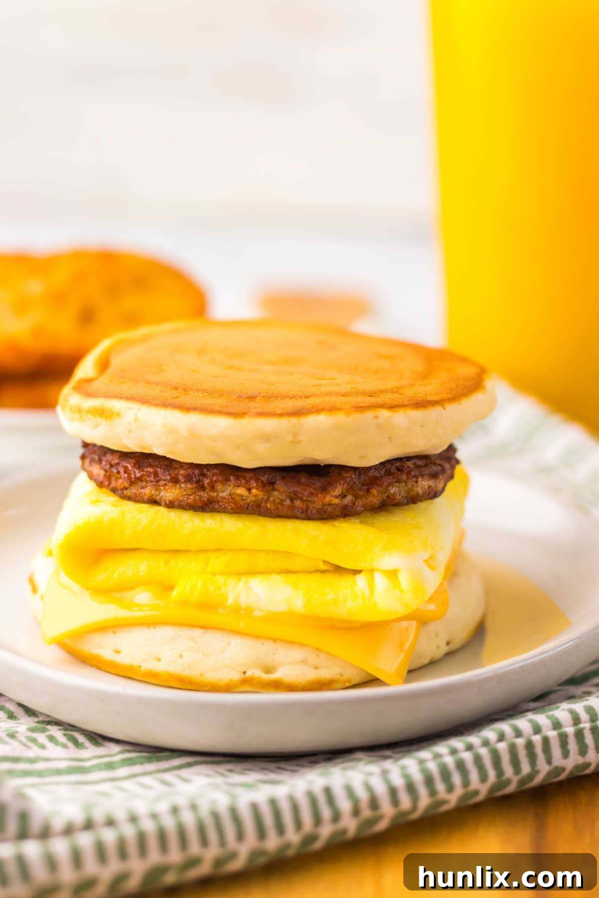 A freshly made copycat McDonald's McGriddle breakfast sandwich on a white plate, showcasing the maple-infused pancakes, sausage, egg, and melted cheese.