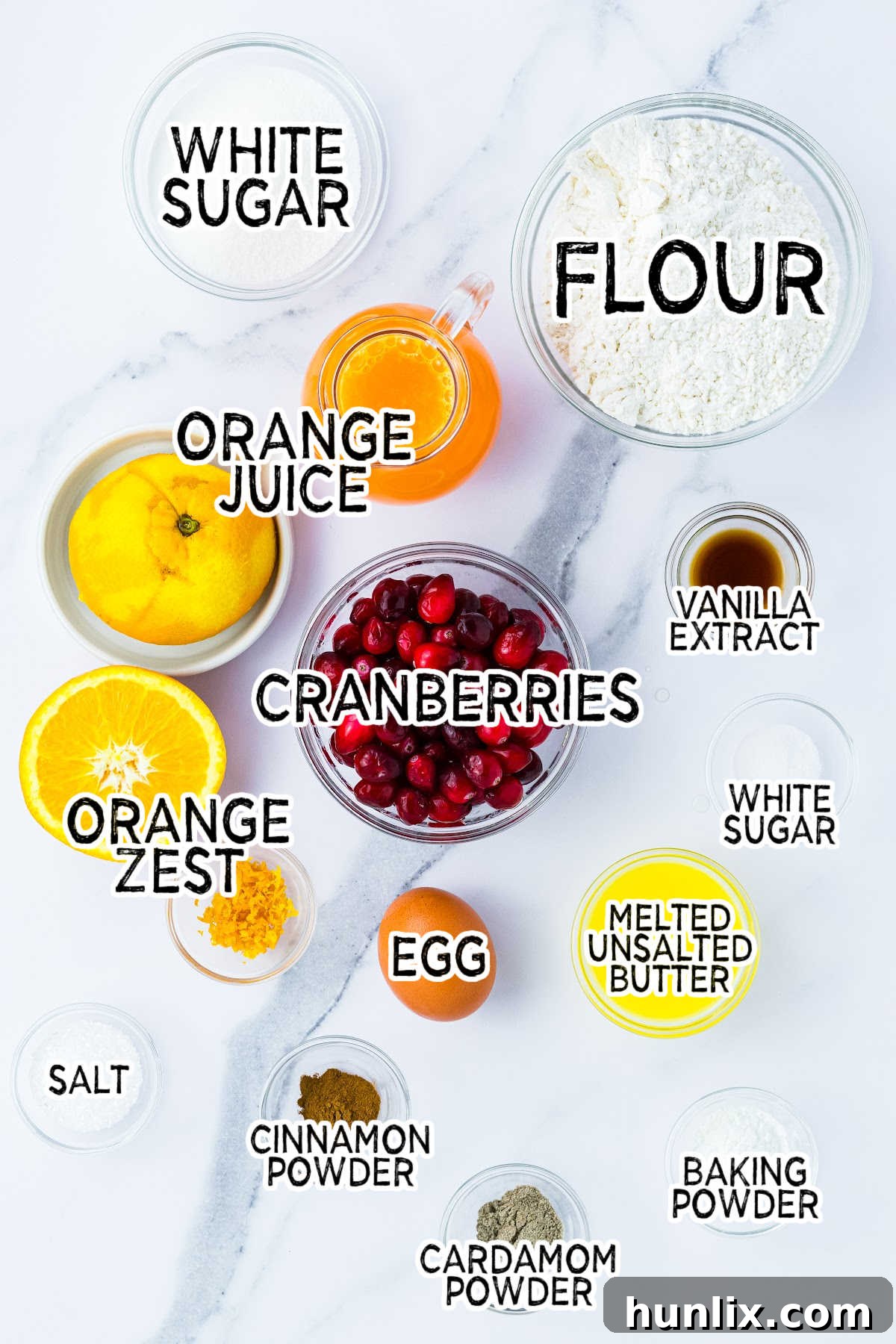 Zesty Cranberry Orange Muffins 3 Ingredients for cranberry orange muffins laid out on a white marble counter.