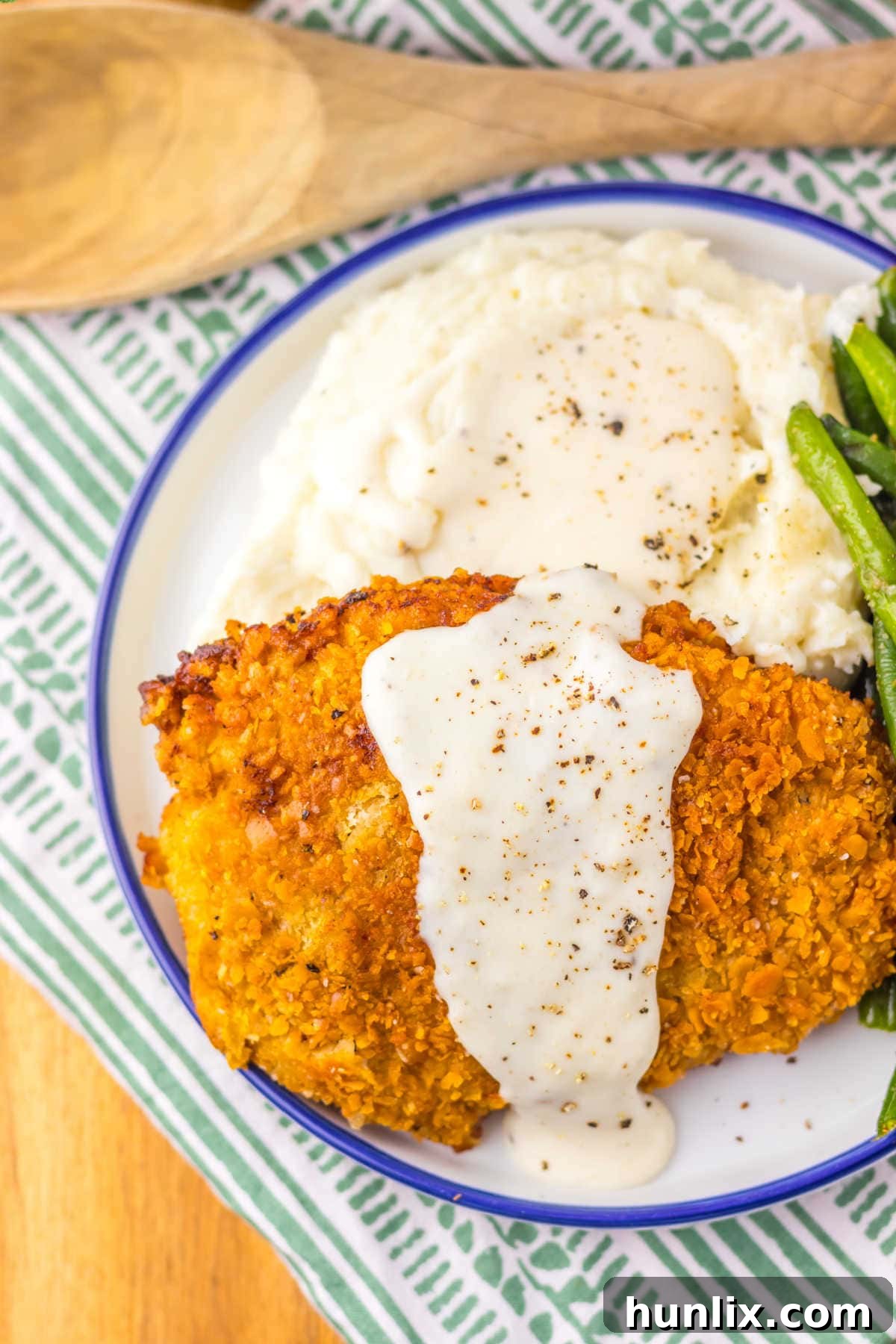 A plate with the recipe on a plate with mashed potatoes and green beans.