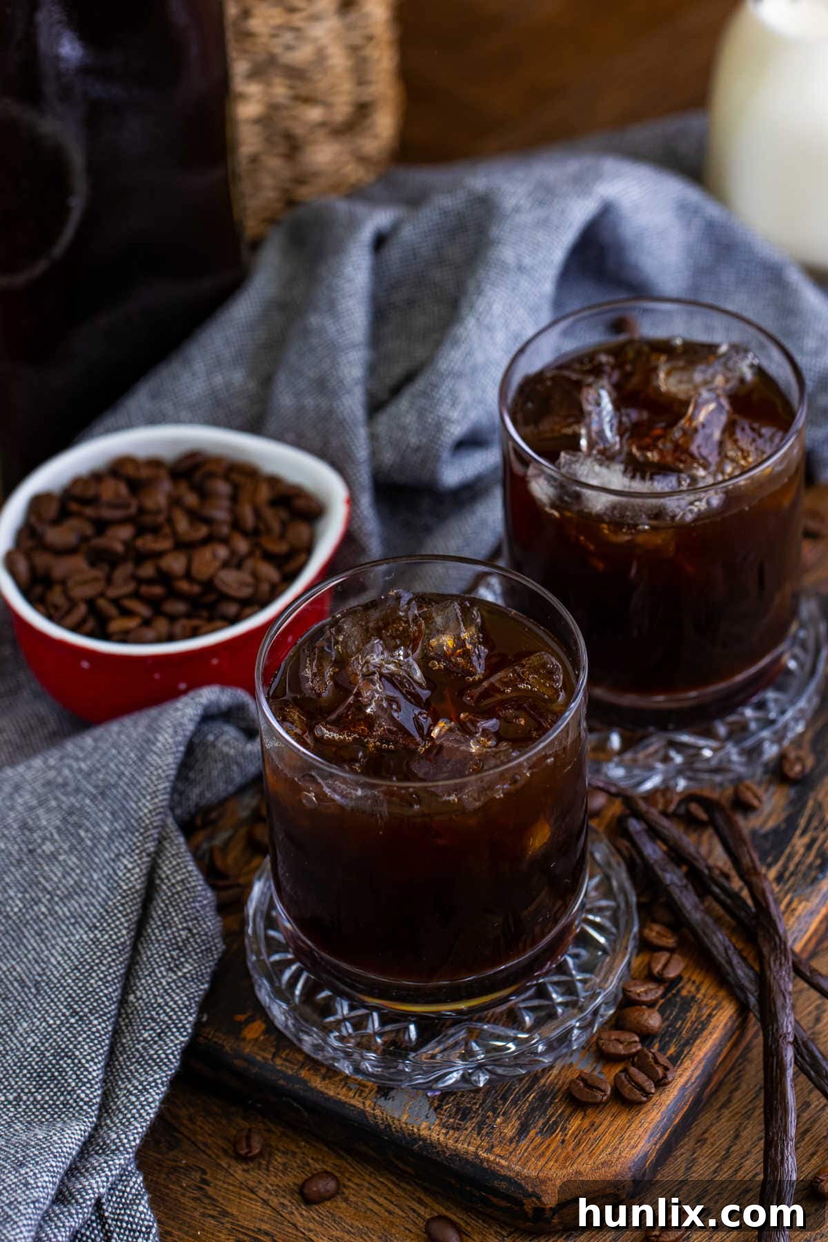 Craft Your Own Coffee Liqueur 6 Glasses of homemade Kahlua artfully arranged with coffee beans and vanilla pods, highlighting its natural ingredients.