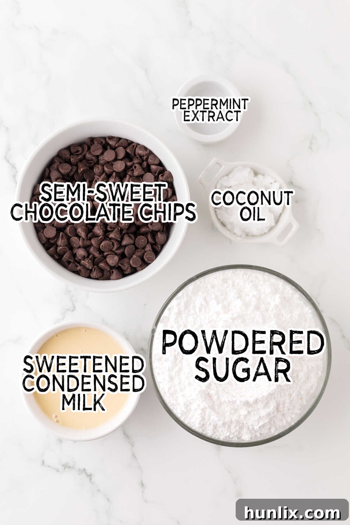 Artisan Peppermint Gems 3 A beautifully arranged collection of the five essential ingredients for homemade peppermint patties laid out on a pristine white marble counter, ready for preparation.
