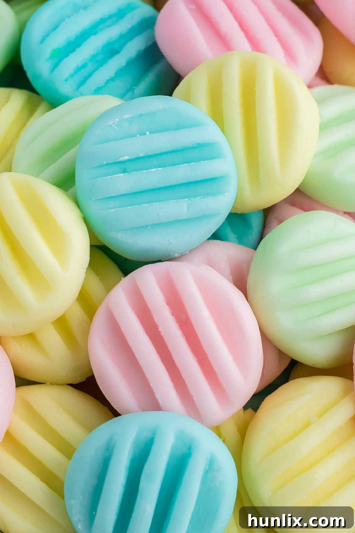 A close-up shot of several pastel-colored cream cheese mints arranged artfully on a plate, highlighting their delicate patterns and vibrant hues.
