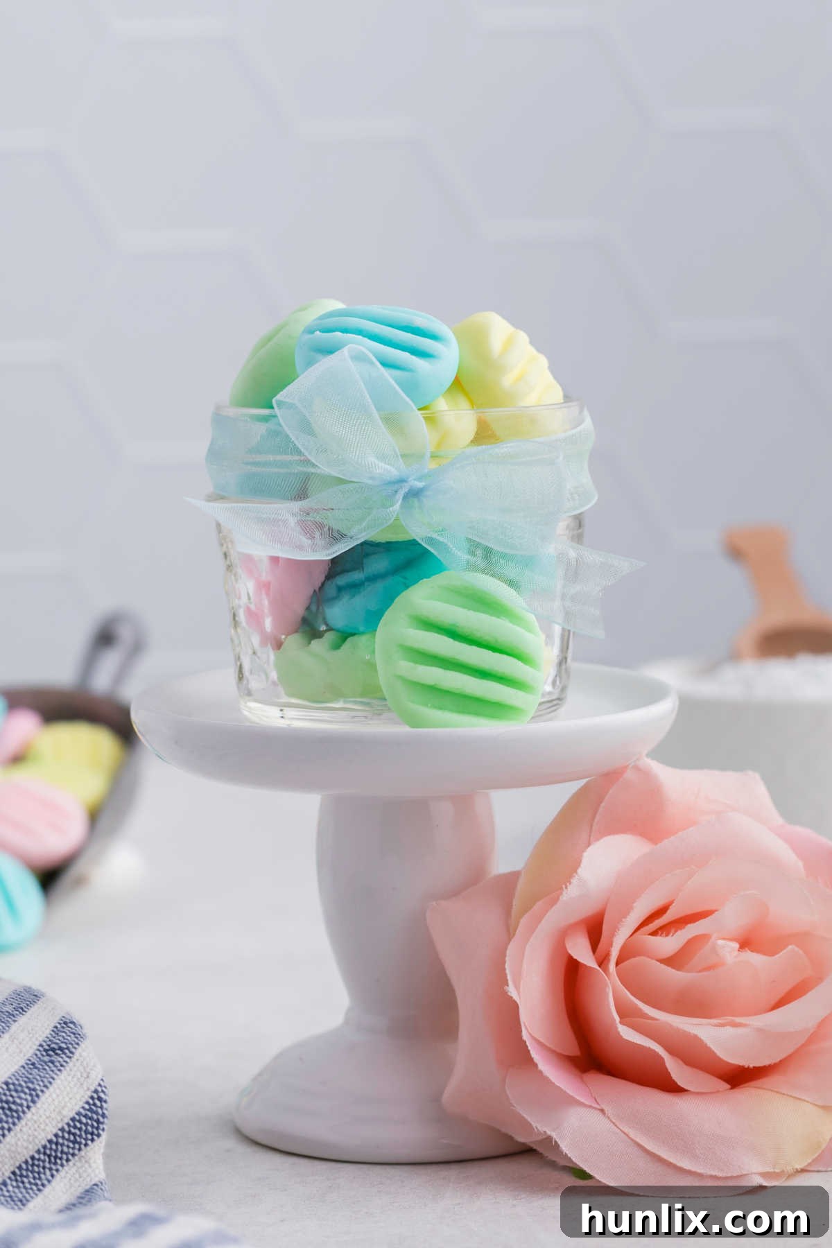 Beautifully arranged cream cheese mints in a clear glass decorative jar, showcasing their vibrant colors and festive presentation.