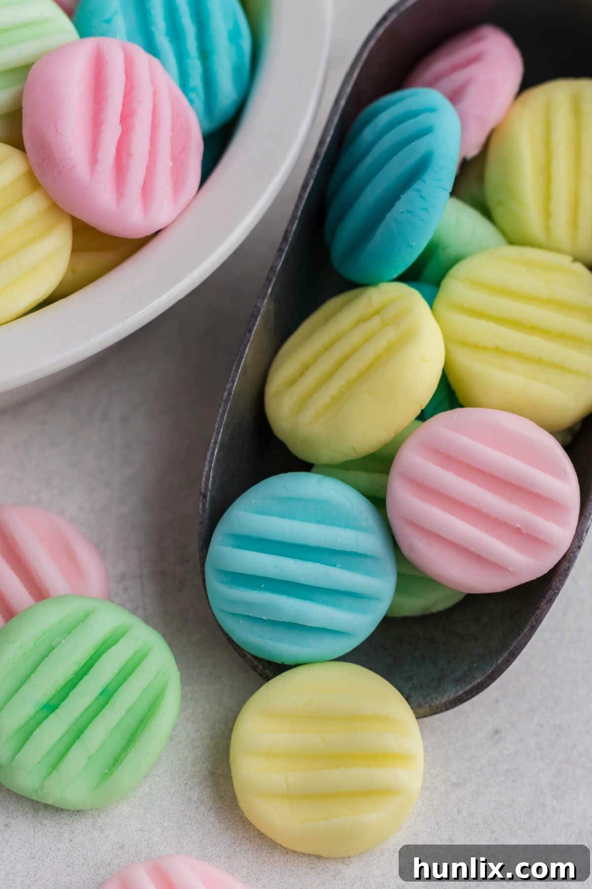 A single cream cheese mint artfully placed on a small silver scooping spoon, ready to be enjoyed.