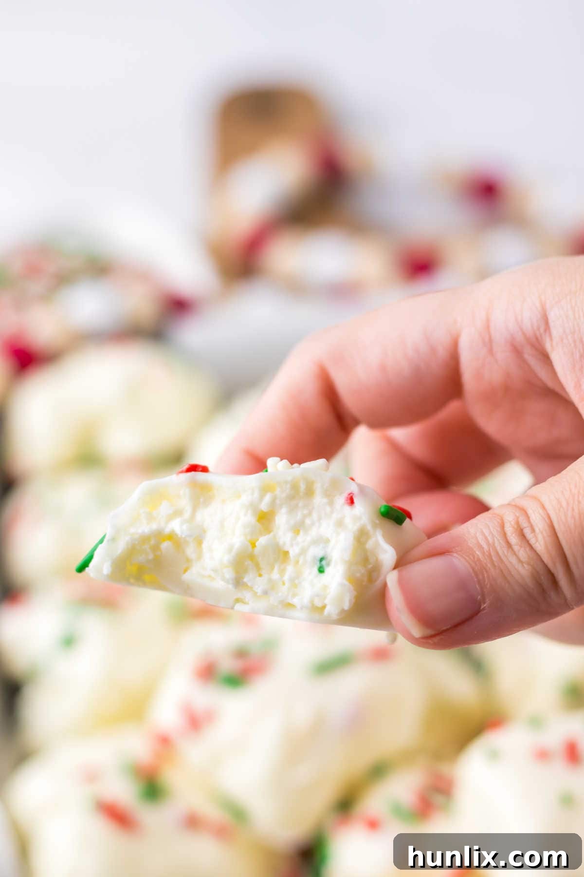 A hand holding a Cool Whip Candy with a bite taken out, showing the creamy interior and crisp coating.