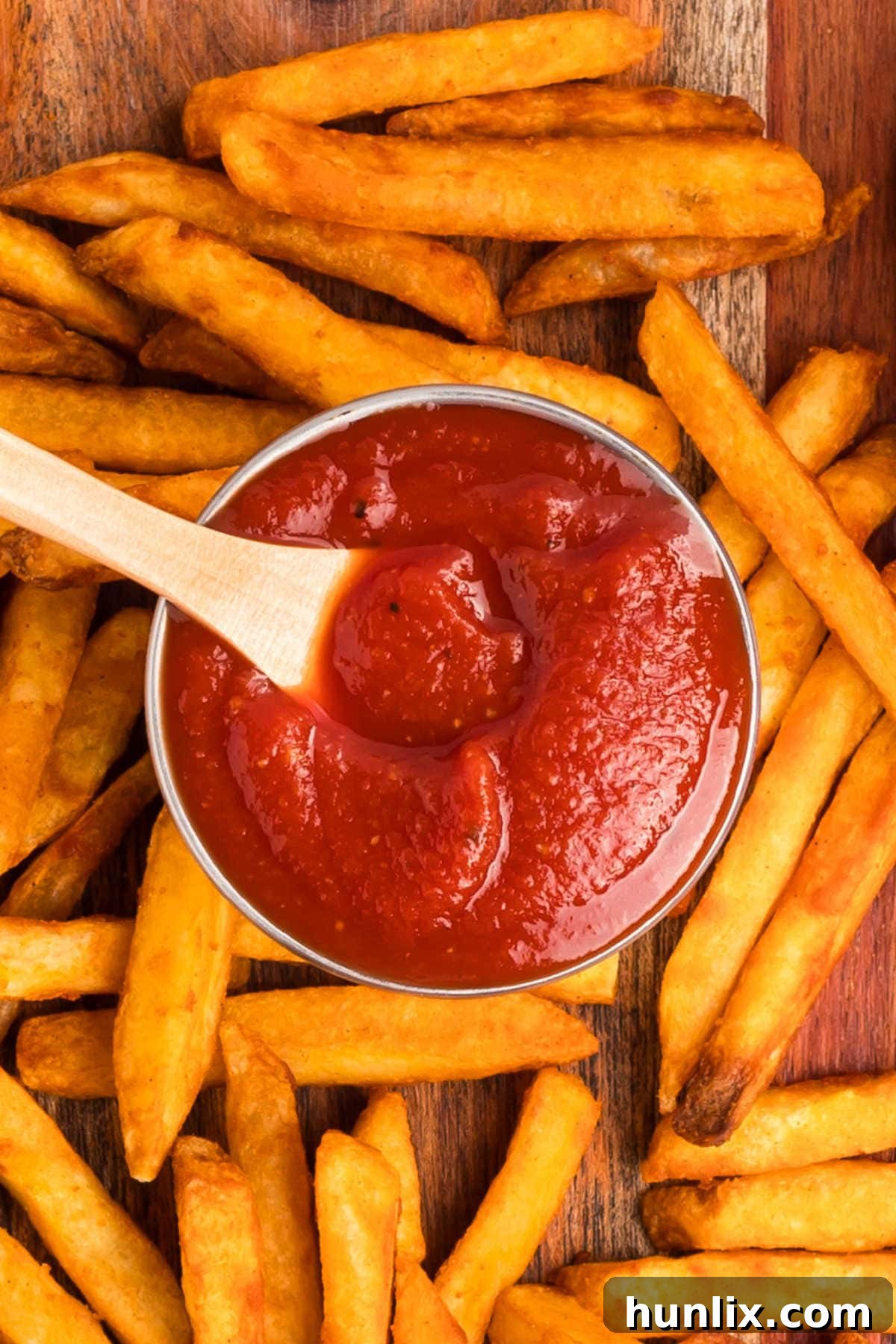 The recipe in a container with a wooden spoon surrounded by fries.