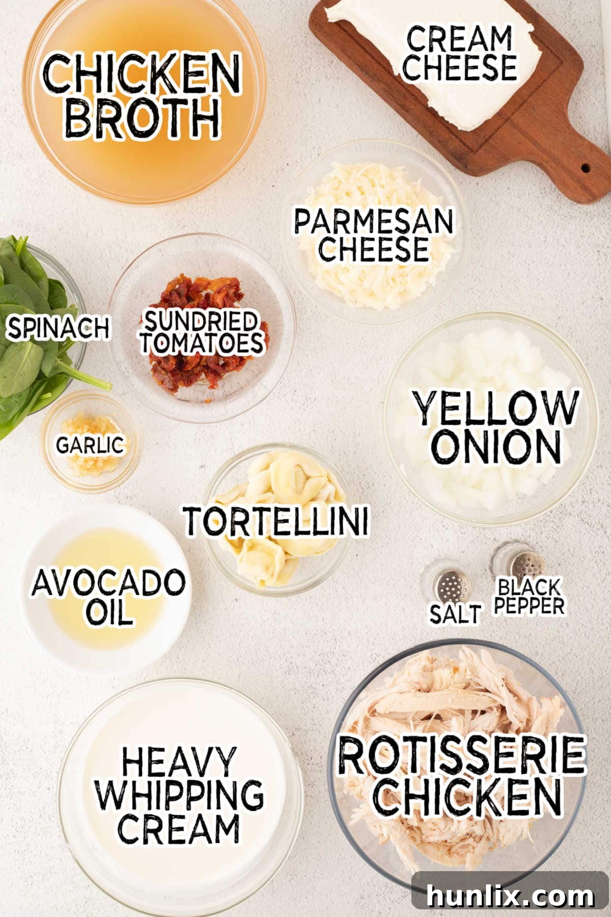 Soulmate Chicken Soup 3 A collection of fresh ingredients laid out on a white background, including onions, garlic, sun-dried tomatoes, and cheese.
