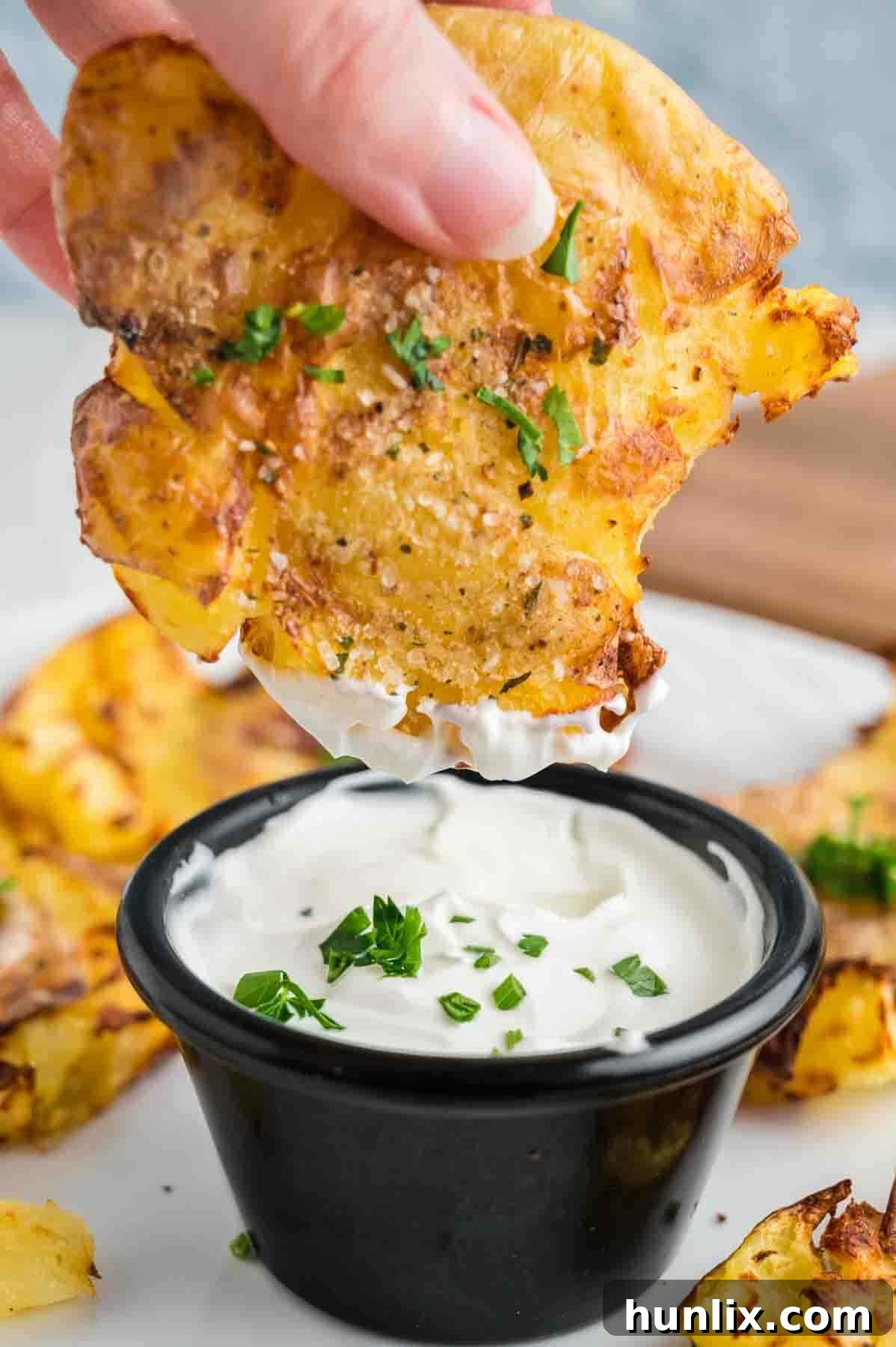 A hand holding an Air Fryer Smashed Potato in ranch dip.