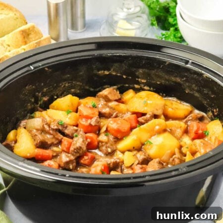 The Slow Cooker Guinness Irish Beef Stew in a black slow cooker, ready to serve.