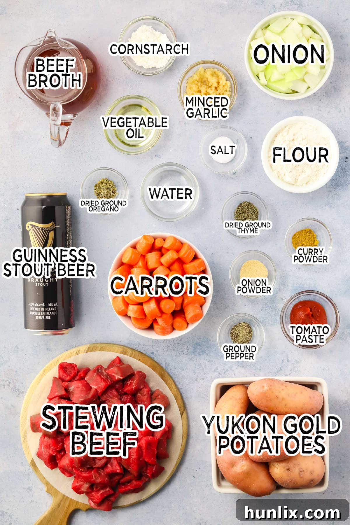 Assortment of fresh ingredients for Guinness Irish Beef Stew arranged on a grey background.