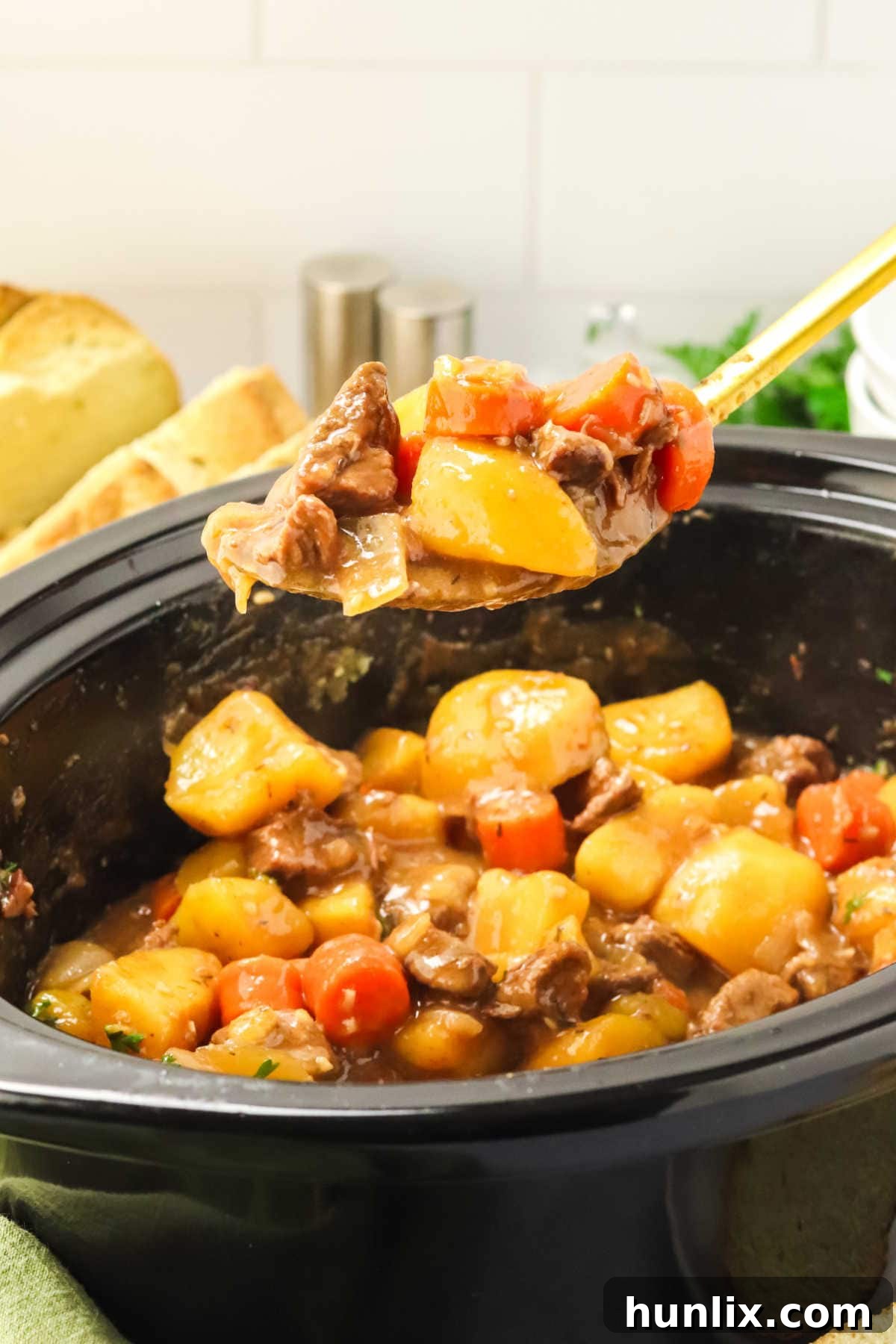 A serving spoon lifting a portion of Guinness Irish Beef Stew, showcasing its rich texture and ingredients.