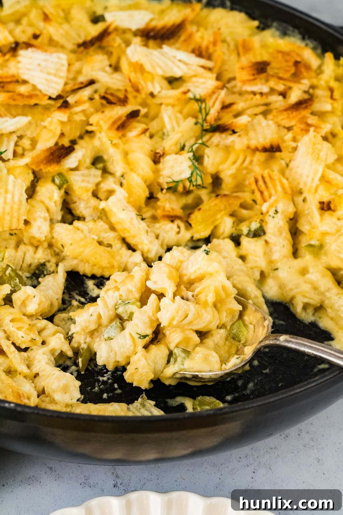 Dill-ightful Macaroni Bake 6 A skillet of Dill Pickle Mac and Cheese with a serving spoon ready to dish out.