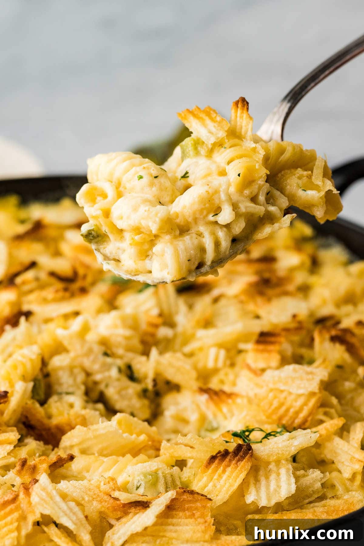 Dill-ightful Macaroni Bake 7 A serving spoon lifting a generous portion of Dill Pickle Mac and Cheese from the skillet.