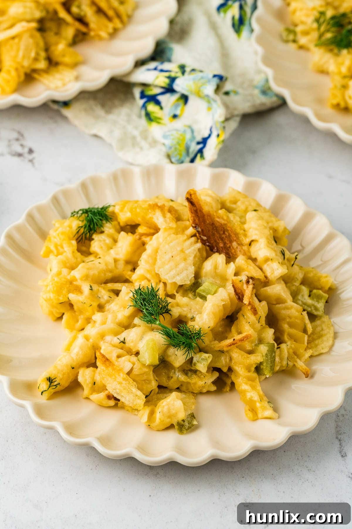 Dill-ightful Macaroni Bake 8 A single serving of Dill Pickle Mac and Cheese on a white plate, garnished with fresh dill.