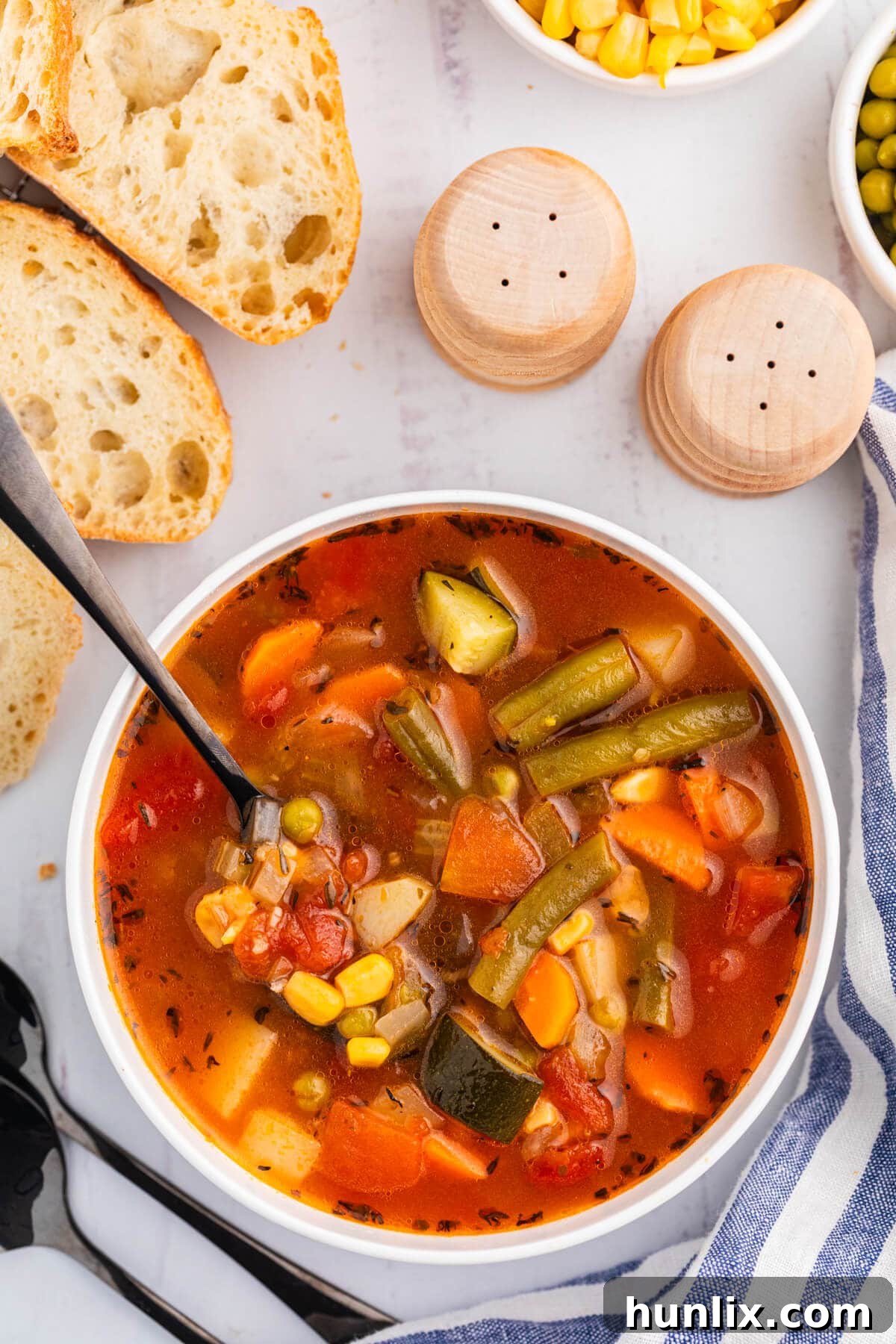 A steaming bowl of hearty homemade vegetable soup, garnished with fresh herbs, and a spoon dipped in, ready to be enjoyed.