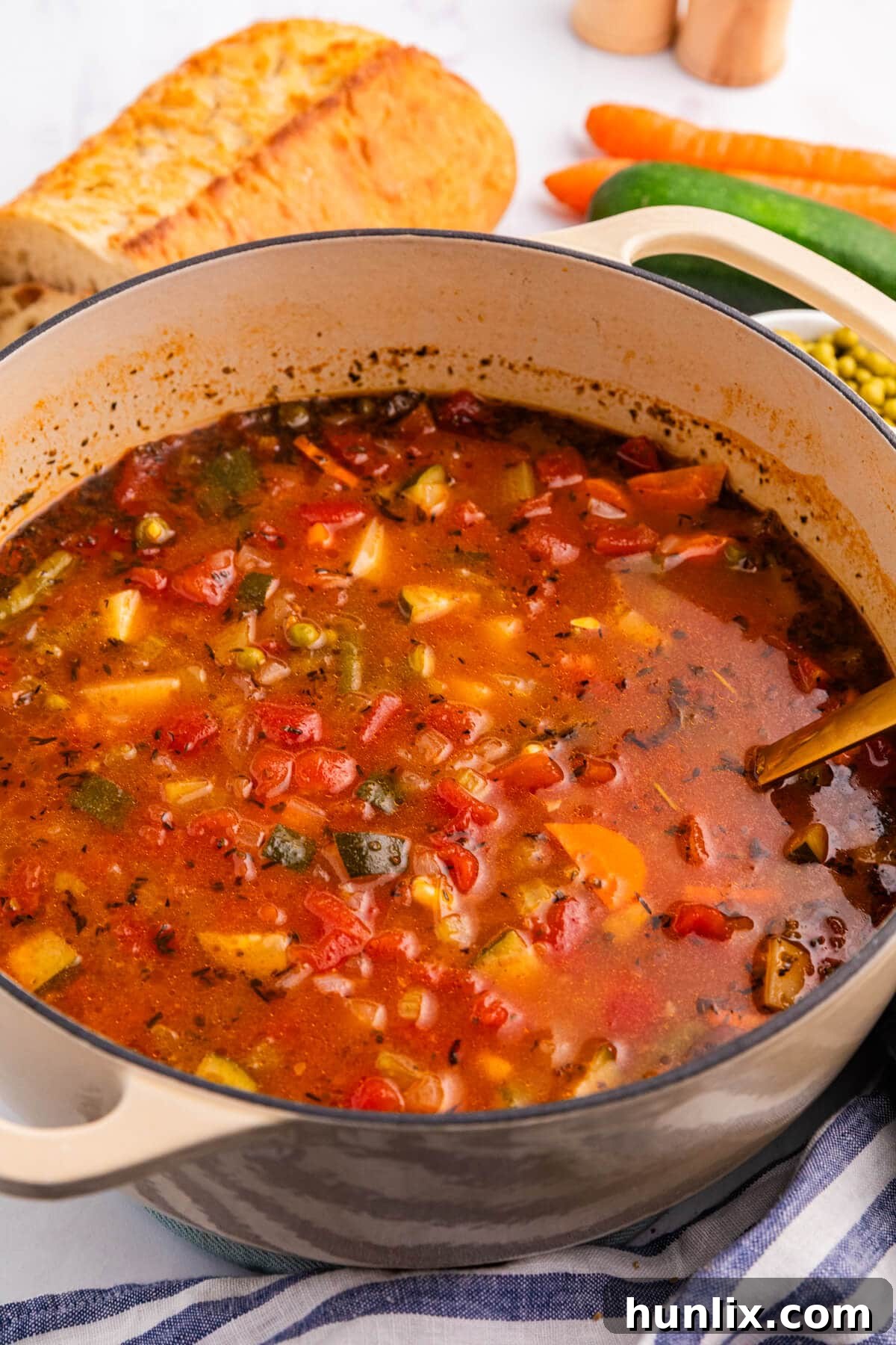 A large pot of vibrant vegetable soup, ready to be served, with a ladle resting inside, showing the rich texture and colorful ingredients.