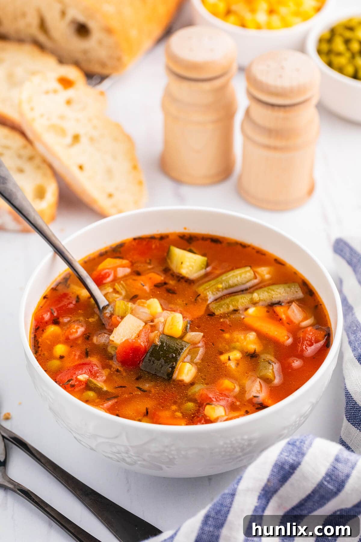 A inviting bowl of vegetable soup, ready to be eaten, with a spoon in it, resting on a rustic wooden surface, highlighting its warmth and comfort.