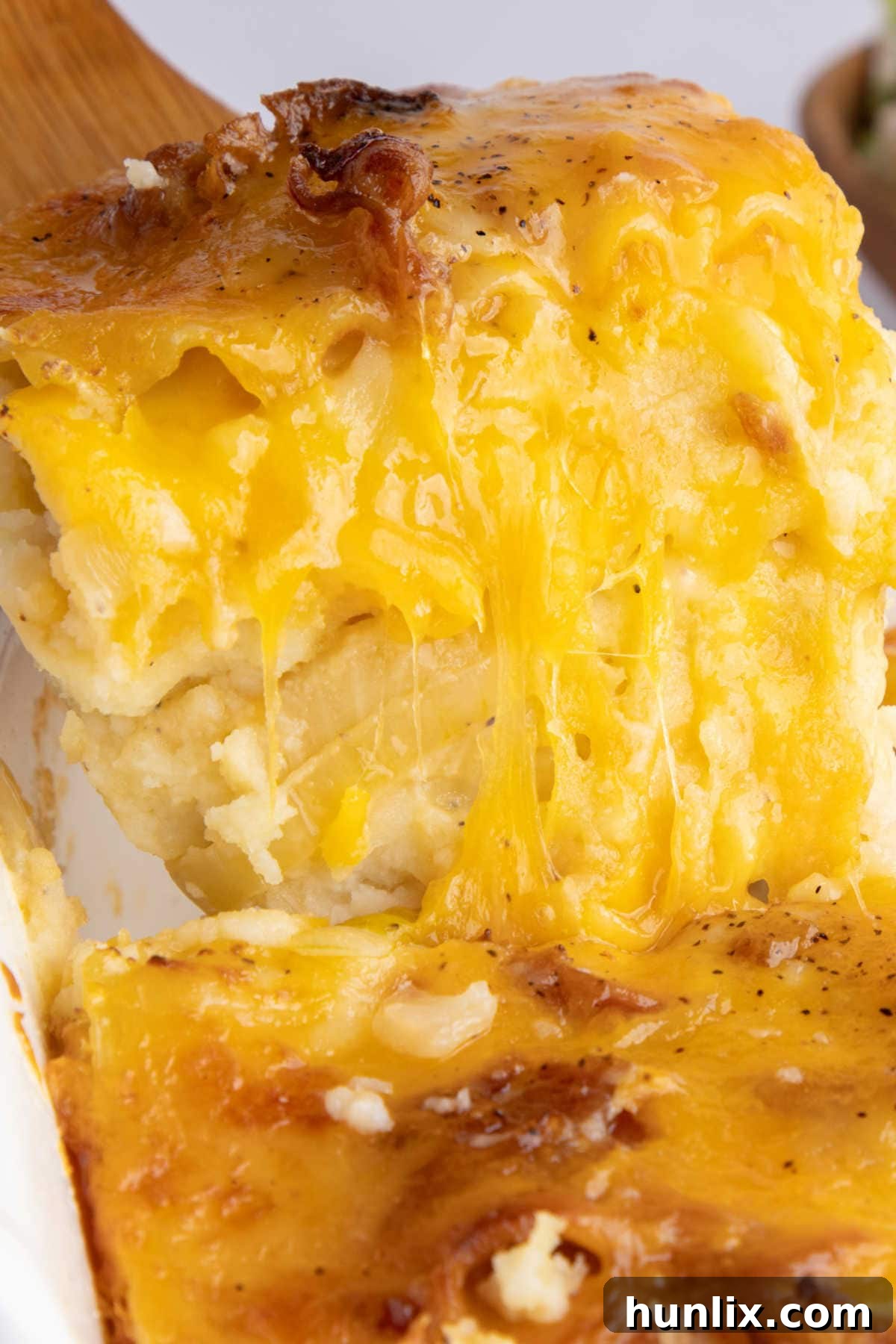 A wooden serving spatula lifting a slice of pierogi lasagna from a pan, showing the distinct layers.